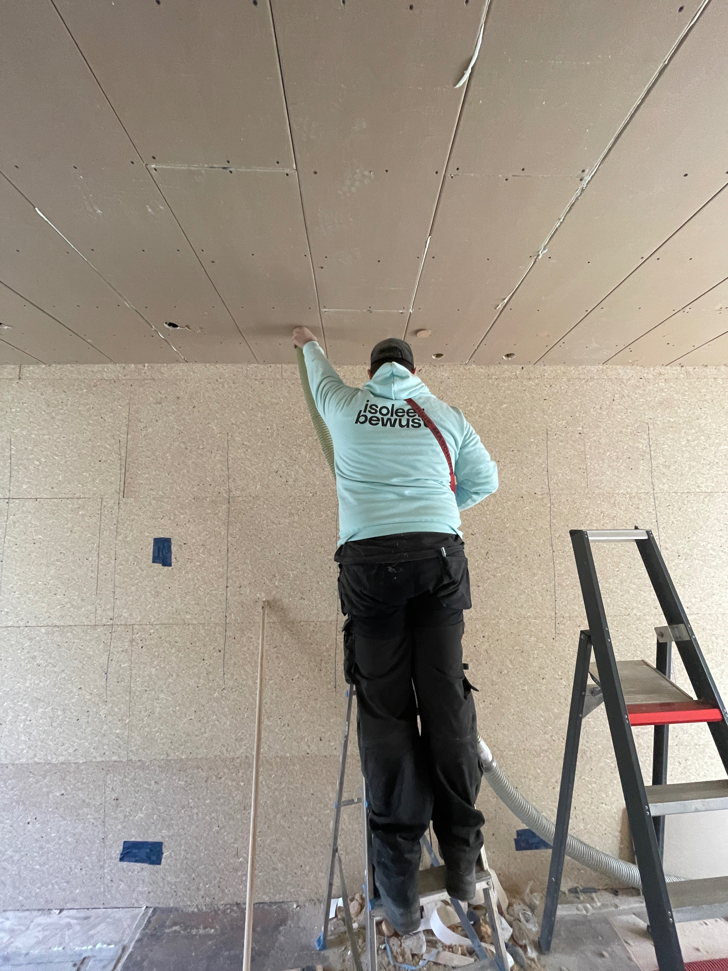 Vakman blaast cellulose via een kleine opening in het plafond